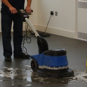 man providing office floor cleaning in a community hall.