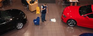 woman providing showroom cleaning services by mopping a car showroom floor