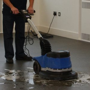 man cleaning a community centre floor using a floor buffer