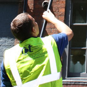 man using the Reach and Wash system to clean some second storey windows outside