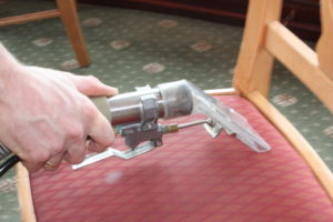carpet cleaner hose head extracting water from an upholstered chair's seat