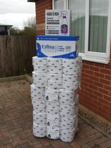 a large stack of toilet rolls and janitorial supplies outside a house.