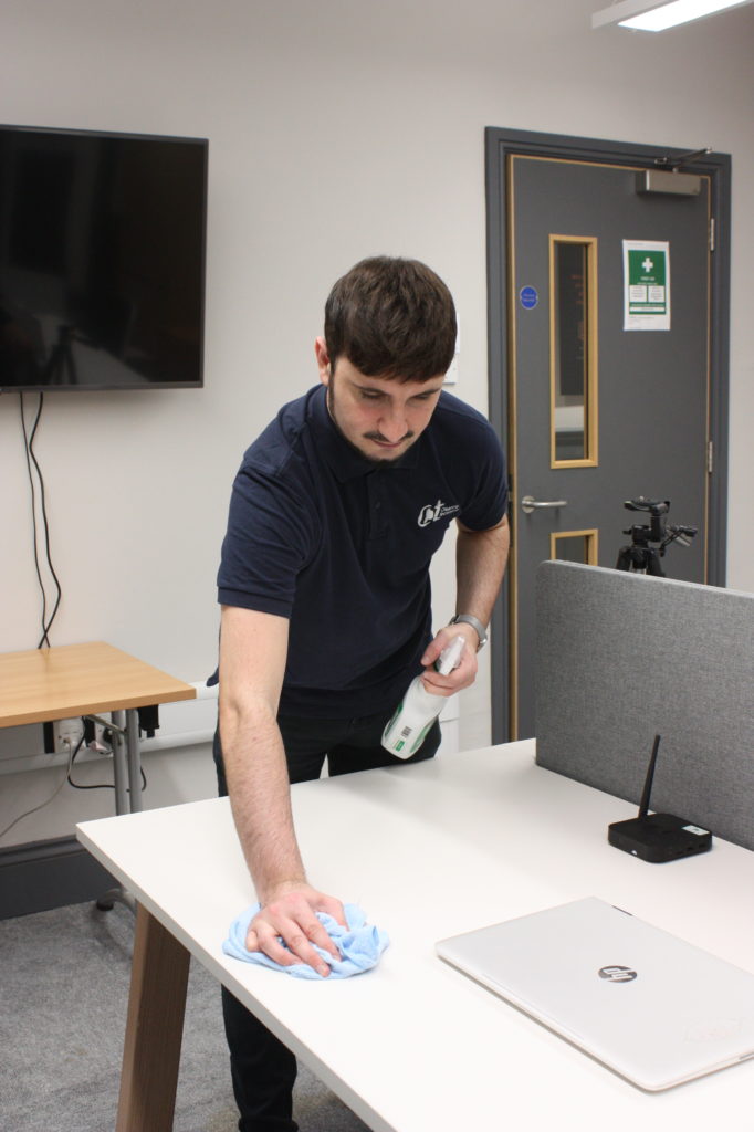 a male cleaner wipes down a desk in Lineview Solution's office space