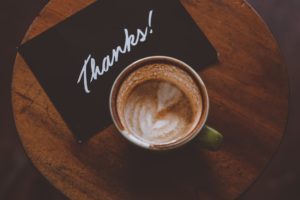coffee cup and thank you card seen from above on a coffee table