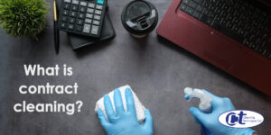 featured image of blog about contract cleaning and its definition showing two gloved hands dusting an office desk.