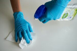 gloved hands disinfecting a surface