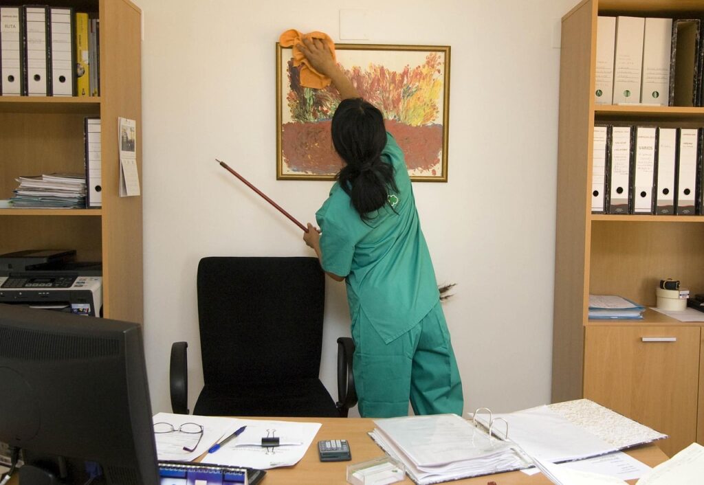 Cleaner cleaning a picture in an office behind a desk. Why is deep cleaning important?
