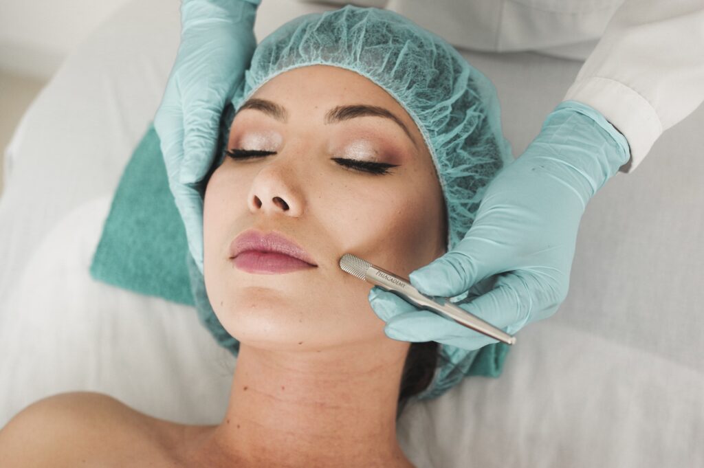 doctor in blue gloves performing laser hair removal on a woman's face.