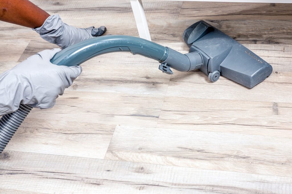 A vacuum cleaner being used to vacuum a laminate floor, showing some of the challenges in the cleaning industry