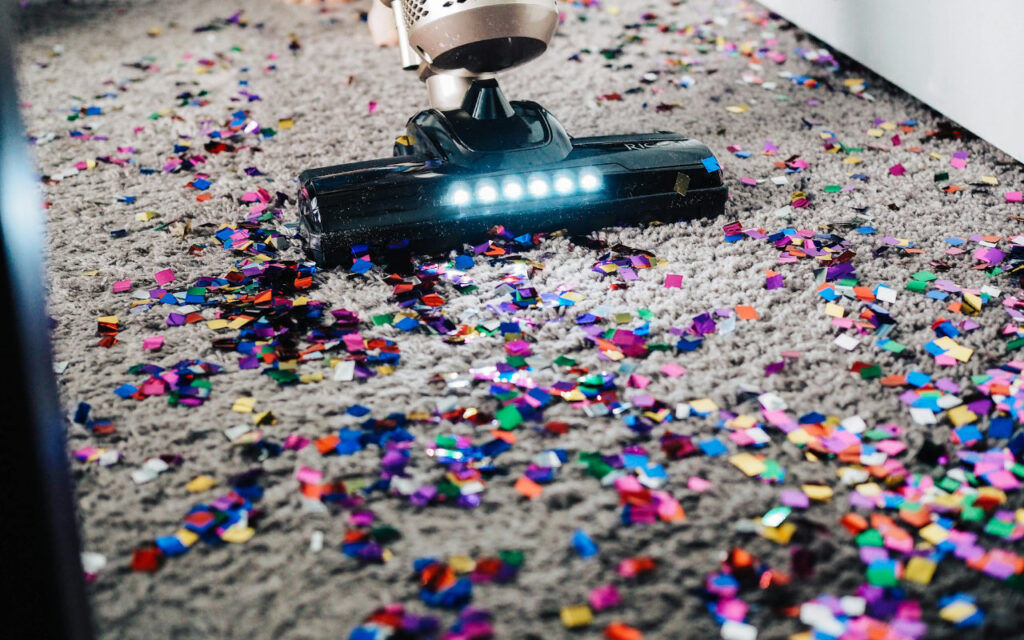 vacuum cleaning conducting commercial carpet cleaning on a rug with confetti everywhere